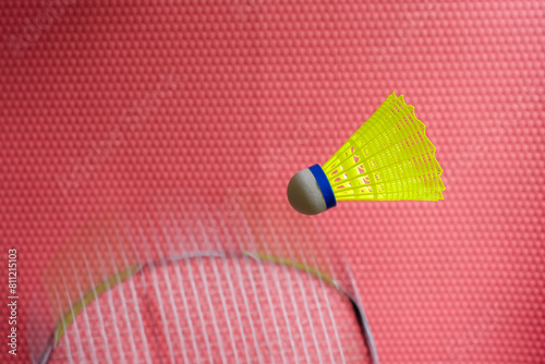 Yellow shuttlecock. Blurred racket movement. Red background. Copy space. 