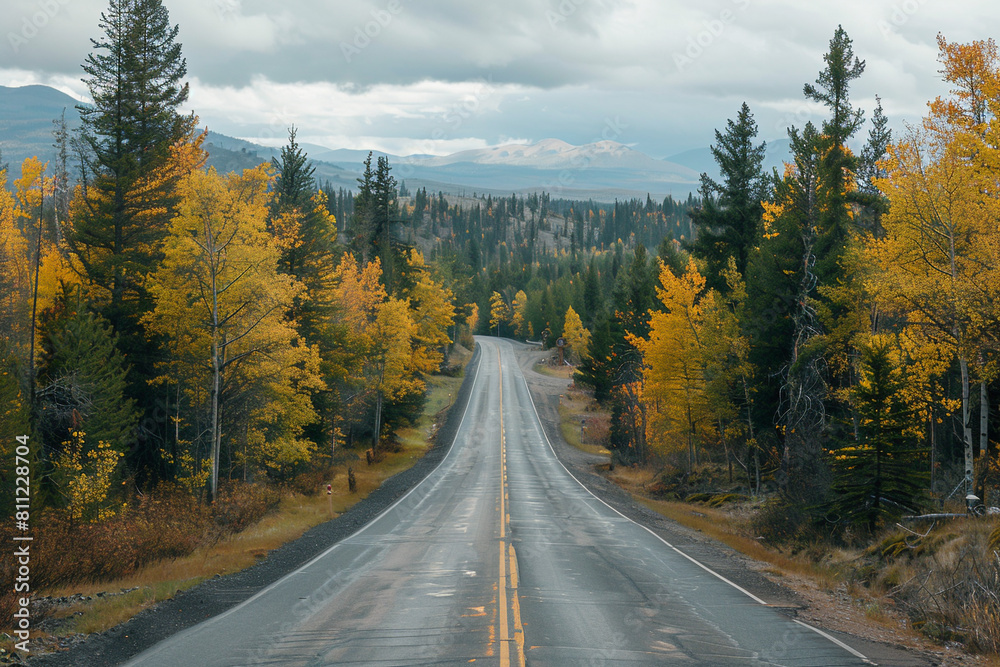 Expansive scenic view of a road leading through a forest with fall colors and mountains in the background on cloudy autumn day, Generative AI