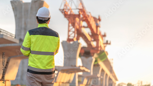 An Asian male engineer works at a motorway bridge construction site,Civil worker inspecting work on crossing construction,Supervisor working at high-speed railway construction site photo