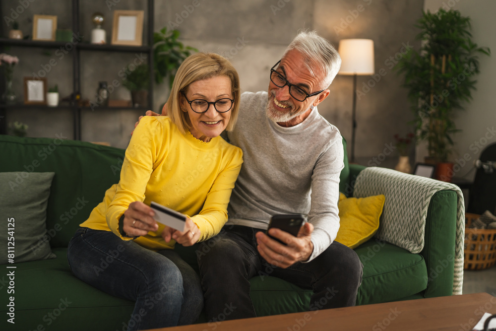 Fototapeta premium Mature caucasian husband and wife shopping online sit at home