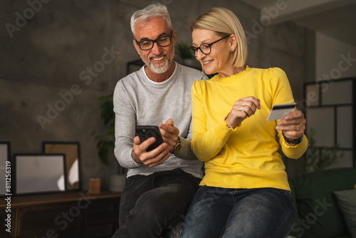 Mature caucasian couple husband and wife shopping online sit at home