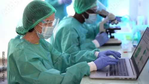 Multiracial scentist working with computer laptop and micoroscope inside laboratory hospital - Research and virus outbreak concept  photo