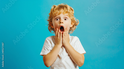 photo of a surprised blond child in full growth on a plain blue background, hypertrophied emotions