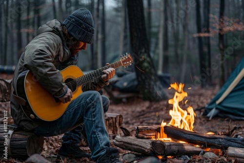 A man sits by a crackling campfire, strumming a guitar, A musician playing a guitar by a crackling campfire in the woods