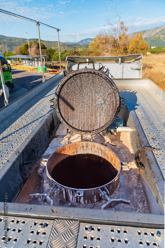 Upper filling port with its lid open of a tanker truck for exclusive transport of bitumen, with the safety rail raised.