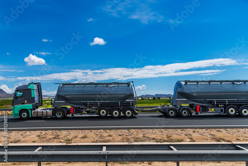 Duo trailer with silo semi-trailers for the transport of powders, traveling on a highway.