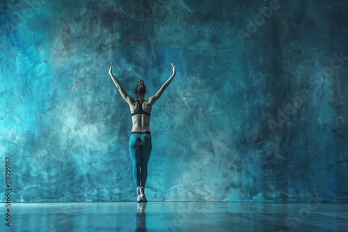 A woman confidently stands in front of a blue wall, A powerful display of balance as a gymnast stands on one hand, their body forming a straight line