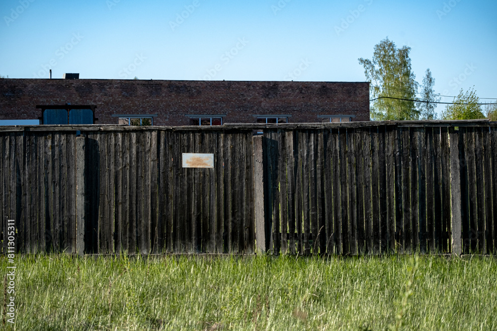old weathered wooden fence around old industrial factory buildings in Latvia Countryside village old weathered wooden fence around old industrial factory buildings in Latvia Countryside village