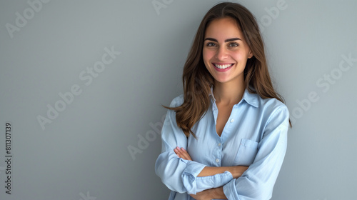 Happy, young, and confident professional woman with a radiant smile, posing with arms crossed on a neutral background