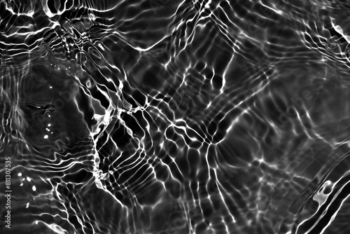 Abstract black water ripple surface. Transparent clear water shadow on black background. Natural light effect on surface of defocus blurred calm water. Natural summer shining pattern texture backgroun