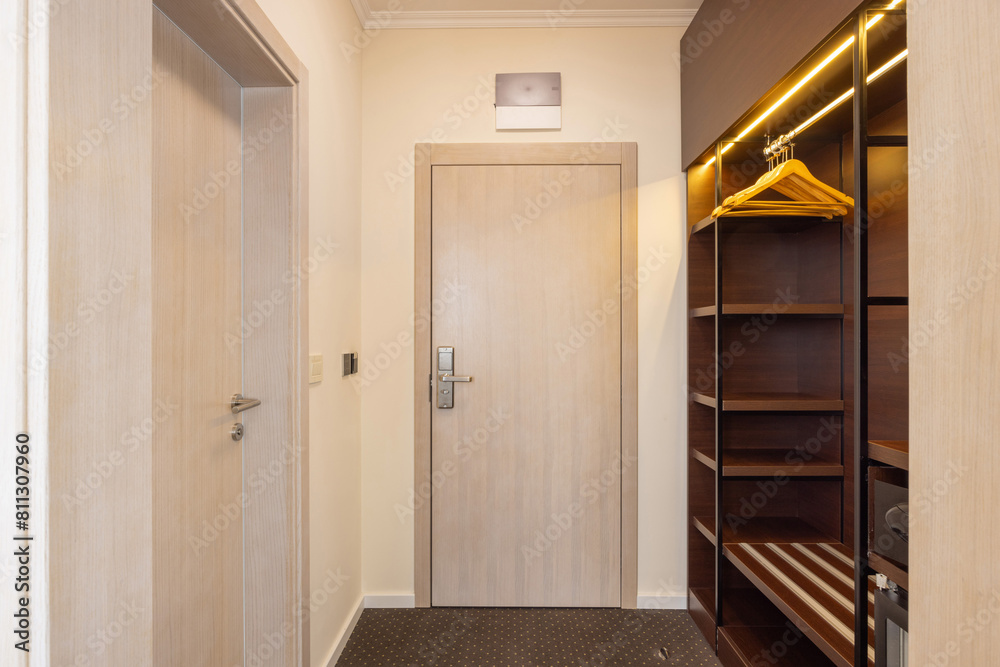Entrance corridor interior with wooden closet and hangers Entrance corridor interior with wooden closet and hangers