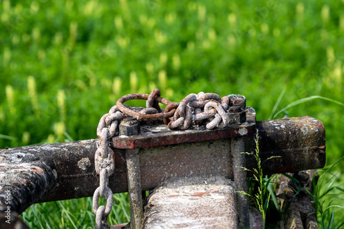 chaines rouillées posées sur un engin agricole rouillé également en extérieur dans un champs
