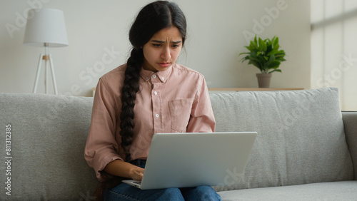 Stressed arabian woman businesswoman student freelancer reading bad news looking at laptop receive message with negative result upset girl at home confused with problem crash failure mistake trouble