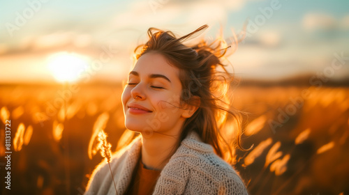 Backlit Portrait of calm happy smiling free woman with closed eyes enjoys a beautiful moment life on the fields at sunset. © EUGINE