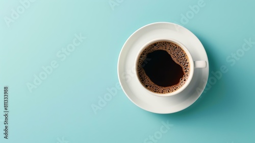 Top view of a white cup of black coffee on a saucer. The cup is placed on a blue background. The image is simple and elegant. photo