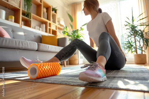 Young woman doing exercises with foam roller un the living room at home. photo