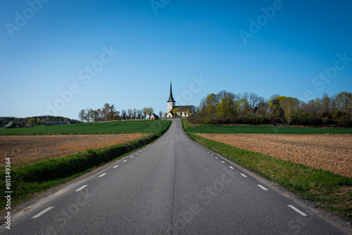 Concept of lonely church on a rock in a landscape: beautiful old lutheran christian church stands on a cliff at a field with road leading to it