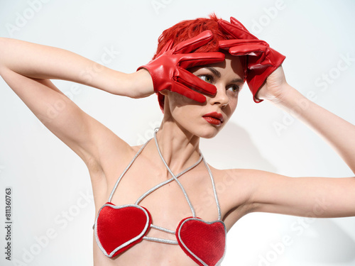 Seductive woman in red bra top and leather gloves holding heartshaped prop in romantic gesture photo