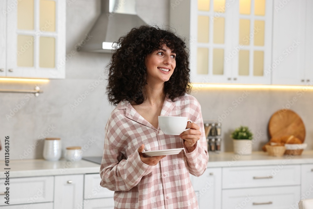 Beautiful young woman in stylish pyjama with cup of drink in kitchen Beautiful young woman in stylish pyjama with cup of drink in kitchen