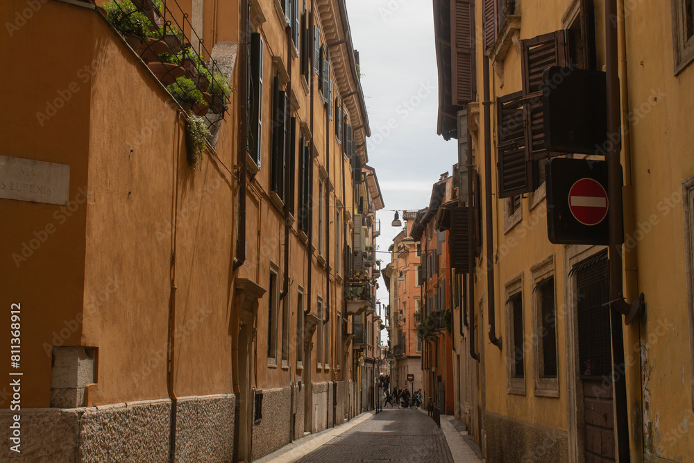 Fototapeta premium Horizontal overall plan photo of buildings with the bright blue sky background on the ancient street in Italy in the city of Verona, Veneto region. Veronese beautiful streets in the summer
