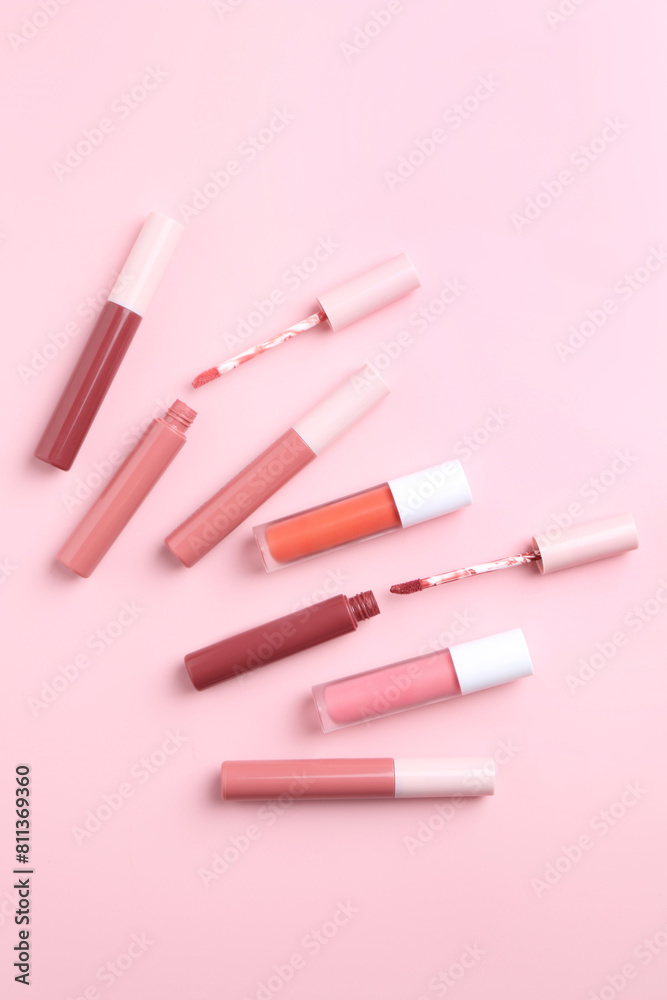 Different lip glosses and applicators on pink background, flat lay Different lip glosses and applicators on pink background, flat lay