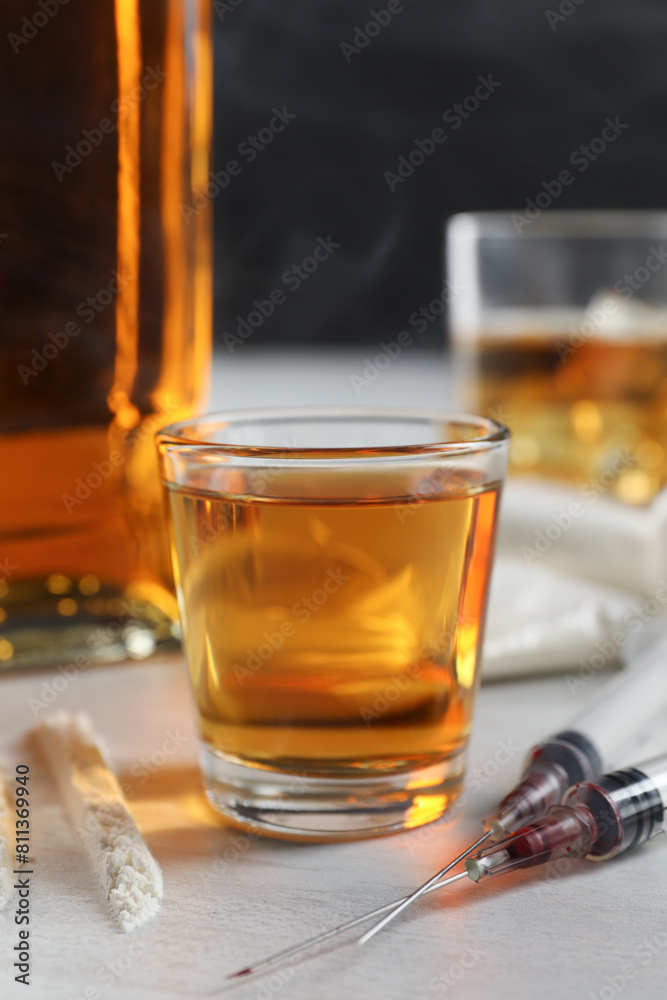 Alcohol and drug addiction. Whiskey in glass, syringes and cocaine on white table Alcohol and drug addiction. Whiskey in glass, syringes and cocaine on white table