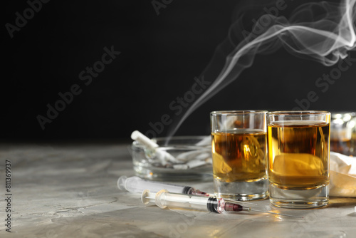 Alcohol and drug addiction. Whiskey in glasses and syringes on grey background, space for text photo