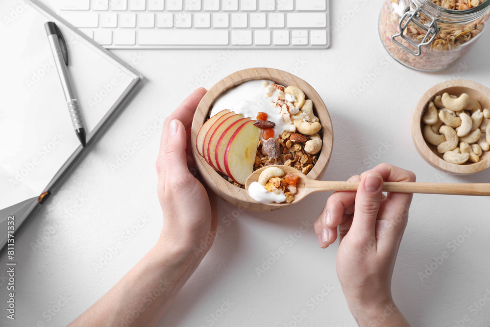 Woman eating tasty granola at workplace, top view Woman eating tasty granola at workplace, top view