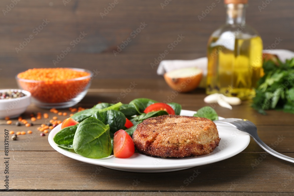 Tasty fried vegetarian cutlet served with spinach and tomato on wooden table Tasty fried vegetarian cutlet served with spinach and tomato on wooden table