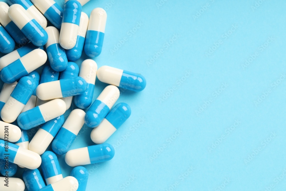Many antibiotic pills and space for text on light blue background, top view. Medicinal treatment Many antibiotic pills and space for text on light blue background, top view. Medicinal treatment