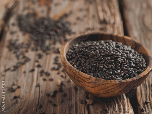 close-up of black oil sunflower seeds in a wooden bowl on rustic background