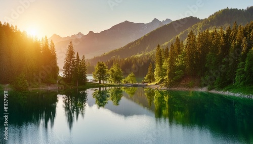 idyllic lake at sunrise a picturesque panorama with majestic mountains and the golden sunlight coming in behind the trees