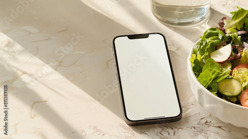 White Screen Smartphone Mockup with Salad on Marble Table with Copy Space: Top View of Blank Screen Mobile Phone, Salad and Glass of Water