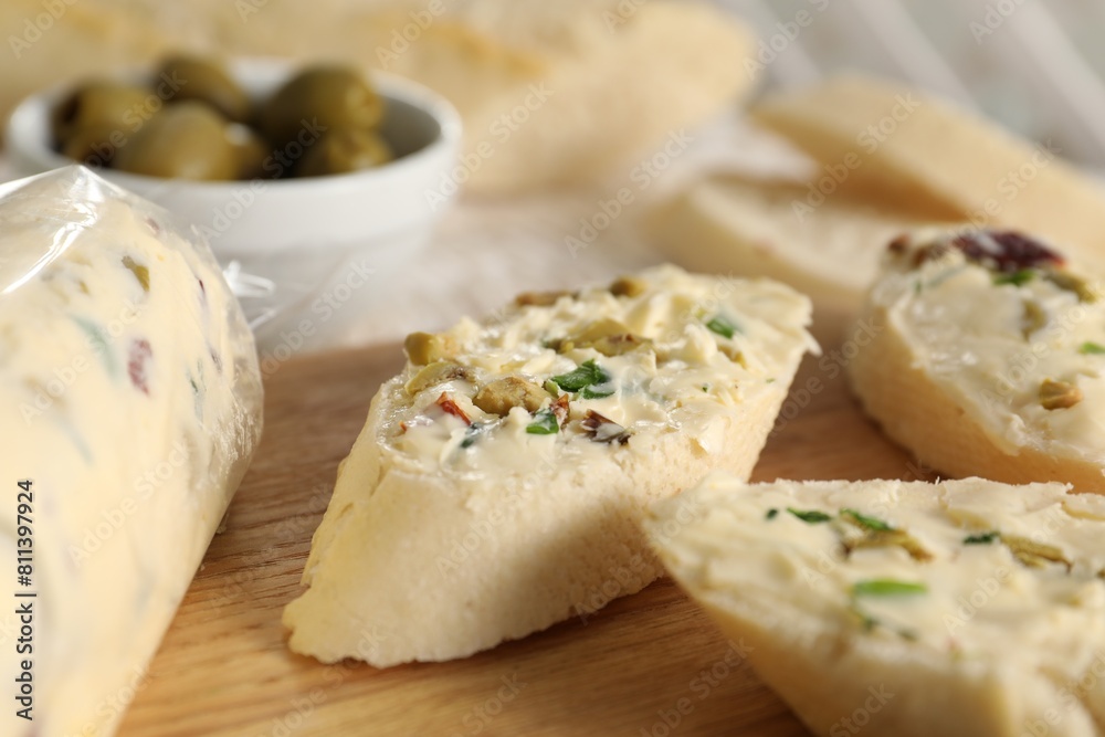 Tasty butter with olives, green onion and bread on wooden board, closeup