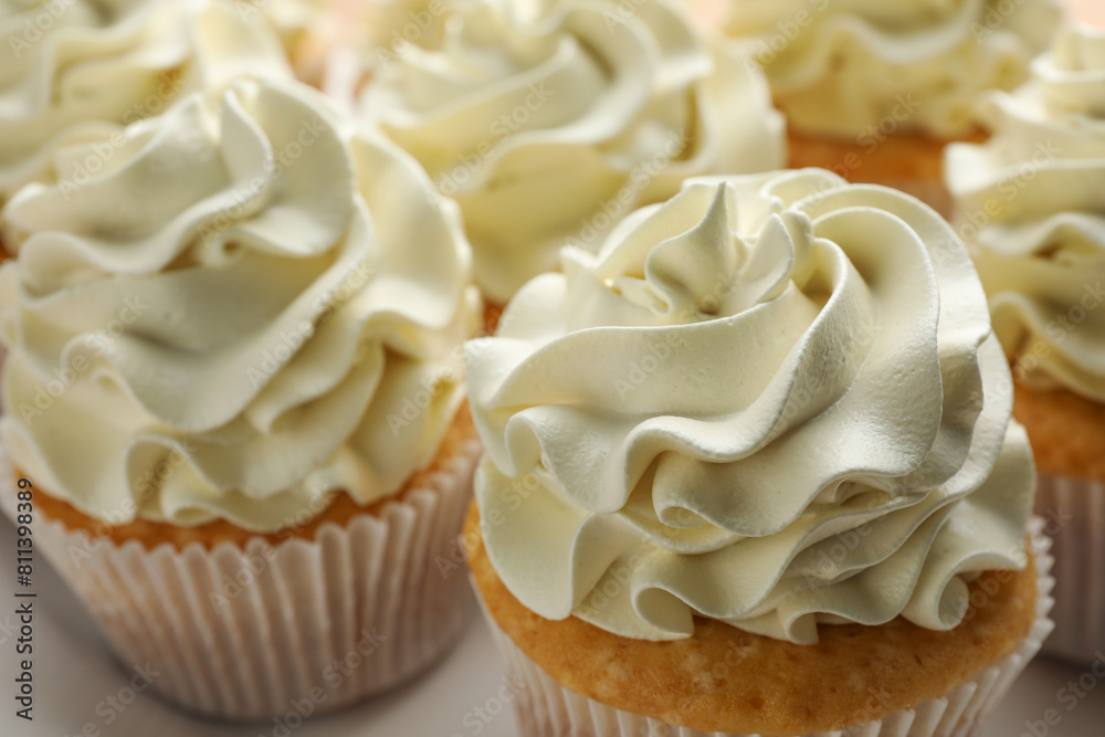 Tasty vanilla cupcakes with cream on plate, closeup Tasty vanilla cupcakes with cream on plate, closeup
