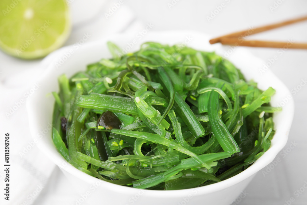 Tasty seaweed salad in bowl and chopsticks on white table, closeup Tasty seaweed salad in bowl and chopsticks on white table, closeup