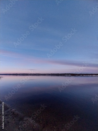 A panoramic view of the lake at dusk, with clear blue skies and gentle ripples on its surface. 