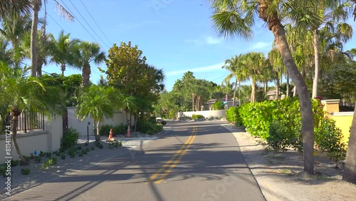 Driving on Florida scenic road. Car point of view of Casey Key coastal neighborhood with tropical nature and southern architecture.