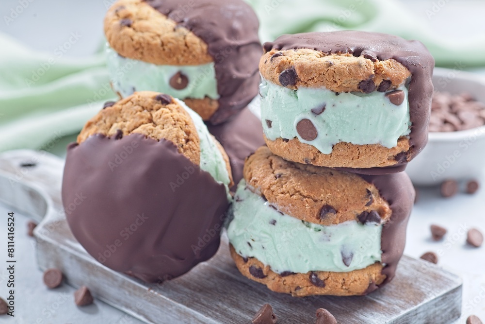 Chocolate covered ice cream sandwiches, mint chocolate chips ice cream , on wooden board, horizontal Chocolate covered ice cream sandwiches, mint chocolate chips ice cream , on wooden board, horizontal