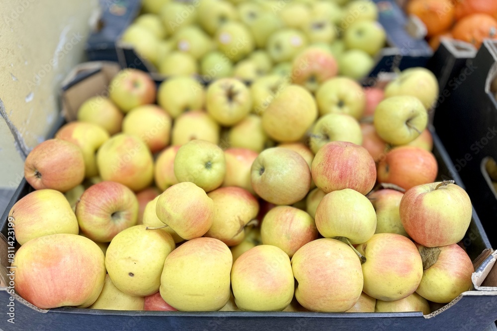 Box filled with fresh natural bio organic red yellow green apples placed on counter in local food market. Close-up Box filled with fresh natural bio organic red yellow green apples placed on counter in local food market. Close-up