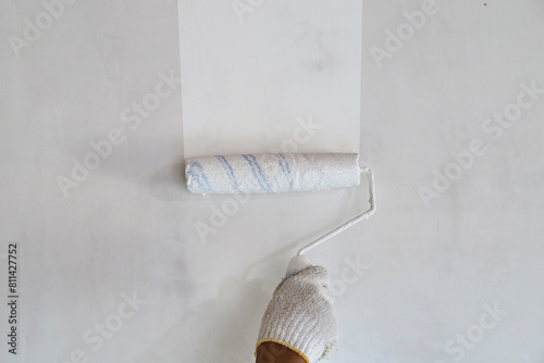 Painter hand holding roller brush painting new white wall, diy interior exterior home renovation
