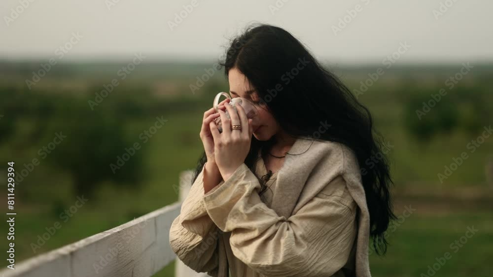 Relaxed young woman traveler enjoying cup of coffee or tea on warm sunset or sunrise on the countryside Beautiful girl taking a sip of coffee or tea with incredible view on village green field alone Relaxed young woman traveler enjoying cup of coffee or tea on warm sunset or sunrise on the countryside Beautiful girl taking a sip of coffee or tea with incredible view on village green field alone