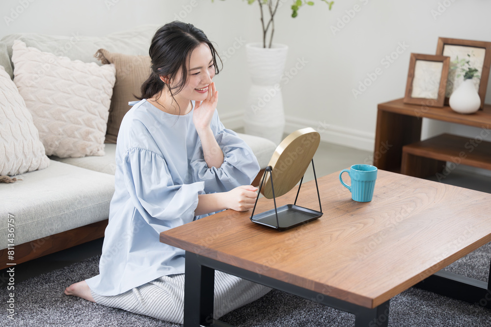 Young woman with pretty smile taking care of skin in room or living room Slightly overhead view Young woman with pretty smile taking care of skin in room or living room Slightly overhead view