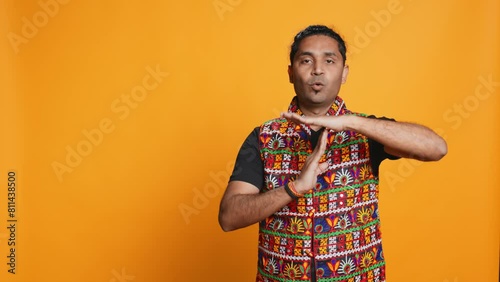 Portrait of assertive indian man asking for timeout, doing hand gestures, feeling fatigued. Firm person doing vehement pause sign gesturing, wishing for break, studio background, camera B