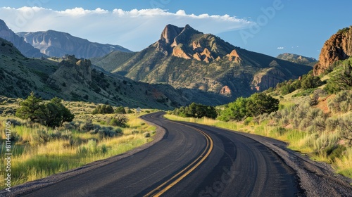 Country road winding through the landscape, rocky mountains towering in the background, under bright, clear lighting