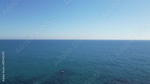 Aerial view from a drone flying over 2 persons on paddle boards, seascape with clear sky and transparent water, 4K photo