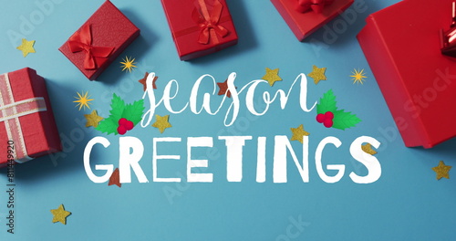 Image of season greetings over presents on blue surface