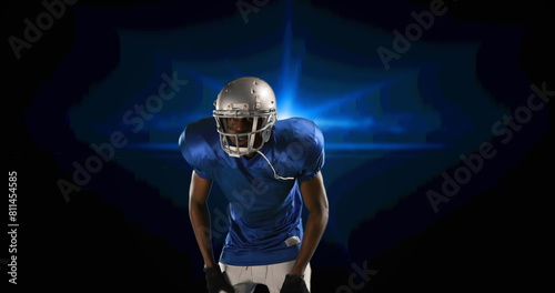 Image of american football player putting helmet on on blue glowing background