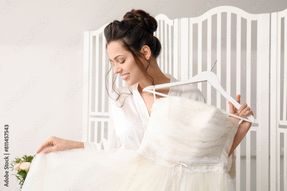 Young bride with her wedding dress in bedroom Young bride with her wedding dress in bedroom