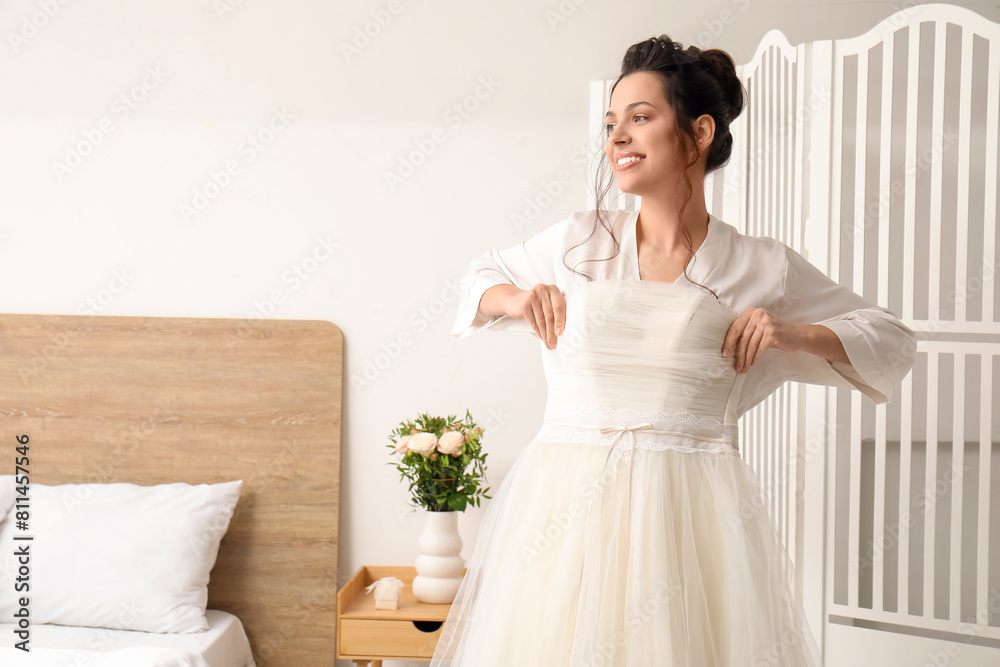 Young bride with her wedding dress in bedroom